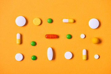 Multi-coloured medicaments on yellow background horizontal flat lay pattern shot