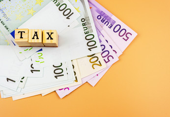 the word tax and the currency of the European Union of different denominations on an orange background 3