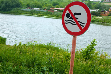 sign on the Bank of the river it is forbidden to swim in the grass on a summer day