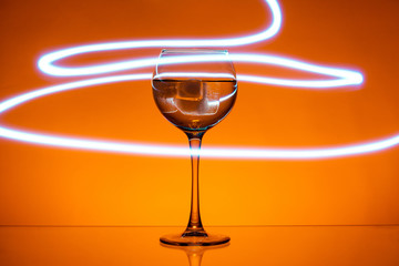 Cocktail in a glass wine glass with neon mint stripes on a Lush Lava background. Close up