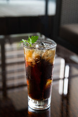 Long Island cocktail drink with plant decoration on a black background.