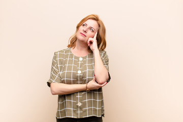 middle age woman with a concentrated look, wondering with a doubtful expression, looking up and to...