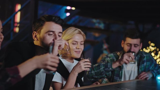 Group of friends divers looking happy enjoying the weekend night together in a bar they drink some beer cocktails and feeling relaxed