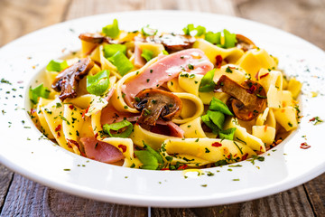 Tagliatelle with ham and chmpignon wooden table