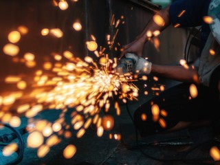 Soft of focus. worker grinding cutting metal sheet with grinder machine overwrites the master of welding seams angle grinder and sparks. 