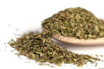 dried lovage herb in wooden spoon isolated on white background. spices and food ingredients. spices and food ingredients