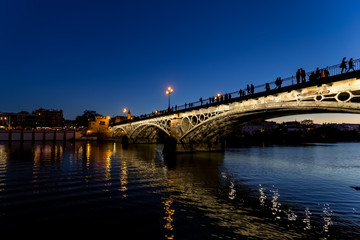Fototapeta na wymiar Triana bridge (Isabel II bridge) over Guadalquivir river at night, Seville, Spain