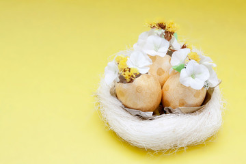 Easter composition: abstract rabbit and golden eggs with flowers in a nest on yellow background