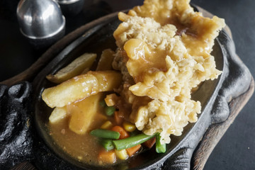 steak tenderloin on a hot plate with potatoes, corn and carrots