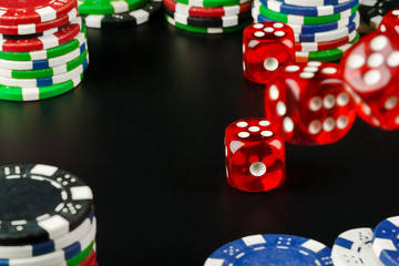 Dice and chips on black table close up