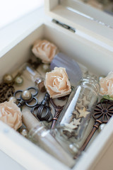 Closeup vintage casket of secrets with mirror, flowers, keys and small glass jars