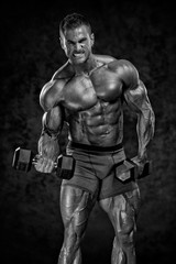 Fototapeta na wymiar Strong Handsome Bodybuilder Lifting Weights. Copy Space