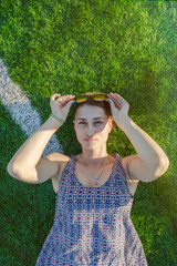 girl in a dress lies on a green artificial field and looks up, vertical photo