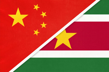 China or PRC vs Suriname national flag from textile. Relationship between asian and american...