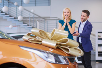 Naklejka premium A man makes a gift - a car to his wife. She is surprised at this. They are very happy about