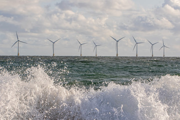 Wind and wave energy. Breaking waves with offshore windfarm turbines background © Ian Dyball