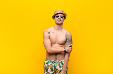 young handsome man laughing shyly and cheerfully, with a friendly and positive but insecure attitude