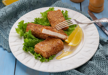 Greek appetizer Feta saganaki. Pan fried sliced feta with honey and sesame seeds served with lemon wedges on white plate.
