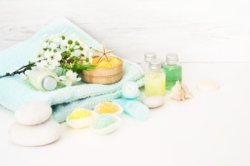 Fototapeta na wymiar Care of a body. Aromatic salt for Spa therapies, cosmetics for a body and acceptance of bathtubs, towel and a spring flower on white wooden background