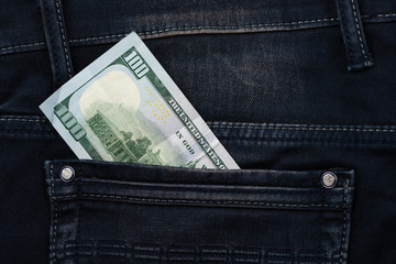 One hundred dollar banknote money in pocket jeans pants background texture. 100 dollar bill close up