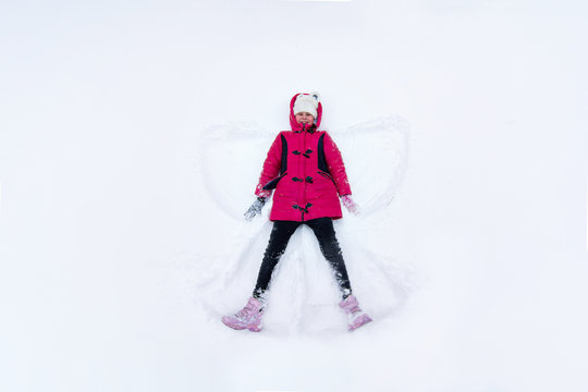 girl lies in the snow and makes an asterisk