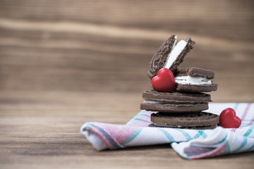 chocolate cookie sandwich on a colored napkin on a wooden background. wooden and red hearts. happy Valentine's day. beautiful picture with biscuits. texture.