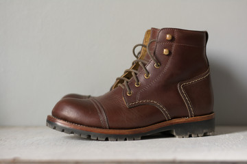 ฺBrown leather shoes with vintage camera on a wooden floor.Brown vintage leather boots aligned selective focus.Men leather shoes 