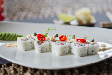 Traditional rolls with fish and rice on a white plate with sauce and wasabi. Japanese food.