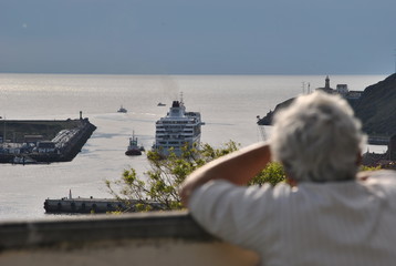 Señora mirando un crucero salir de la ría