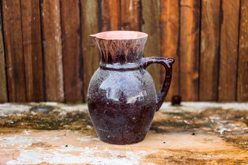 old ceramic glossy jug on a natural vintage table with a wooden background in the background