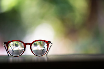 Brown eyeglasses with on wooden table, In bokeh green garden background, Close up & Macro shot, Selective focus, Optical concept