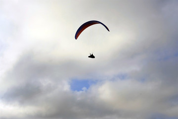 silhouette of a paraglyding man against white clouds in the sky