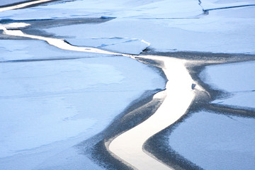Winter sunset landscape of the river bound by ice. Drifting movement of cracked ice floes and...