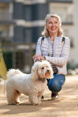 attractive middle-aged blond woman walking with dog in summer city