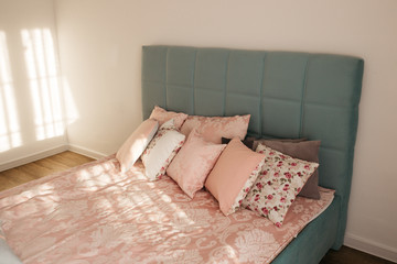 Different pillows on the bed. Close-up pink bedding sheets and pillow on light wall room...
