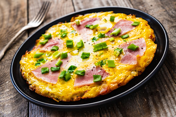 Breakfast - scrambled eggs with ham and vegetables on wooden background