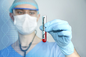 male doctor in blue uniform with a stethoscope in a protective mask and glasses looks at a...