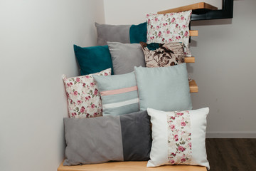 Different pillows on stairs in room, against white wall background