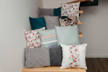 Different pillows on stairs in room, against white wall background