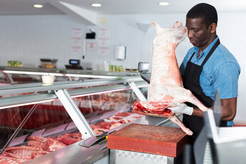 African American male butcher processing carcase of lamb