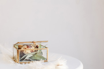 Easter composition. Easter eggs in a glass box on a white and gray background. Greeting card for copy space.