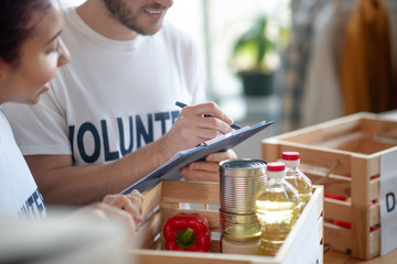Two volunteers packing a box of charity food.