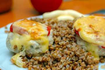 buckwheat porridge with meat patties coated with cheese and tomatoes