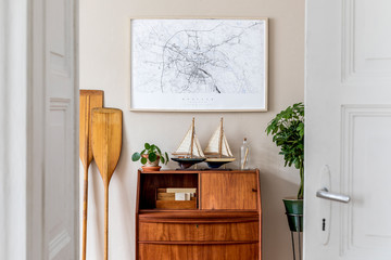 Stylish and vintage interior design of living room with wooden retro commode,  plants, ships,...