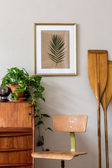 Stylish and vintage interior design of living room with wooden retro commode and chair, plants,...