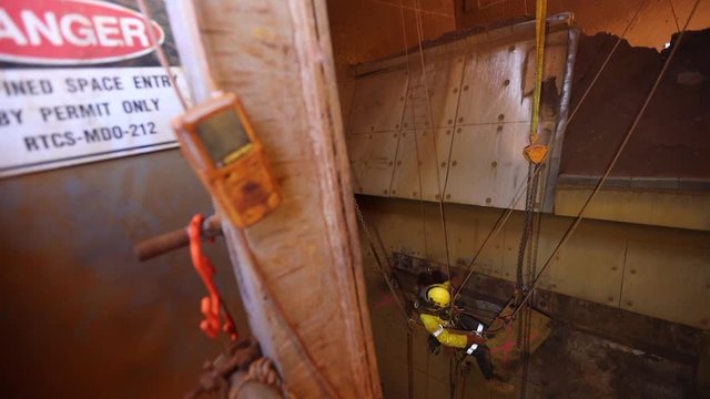 Footage rope access rigger high risk licence worker abseiling working at height confined space restriction area and clipping shackle into crane lifting hook lug construction site Sydney, Australia  