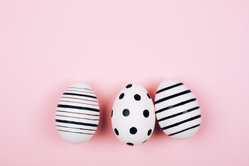 Many easter eggs on trendy pink pastel background. Eggs are hand-drawn. Flat lay style.