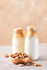 Vegan almond milk and cream in bottles, closeup, brown background. Non dairy alternative milk....