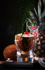 Pina Colada Cocktail in chopped coconut with tropical fruits and bar tools, summer relax concept, copy space