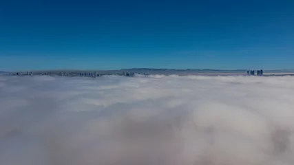 Fotobehang Landscape over the clouds in foggy weather. Hills of buildings in foggy weather. The drone and the top of the fog layer. © Vahit Telli